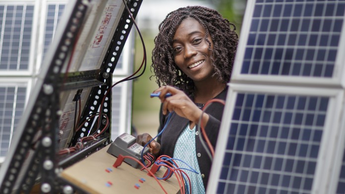 junge Technikerin an einer Photovoltaikanlage in Afrika