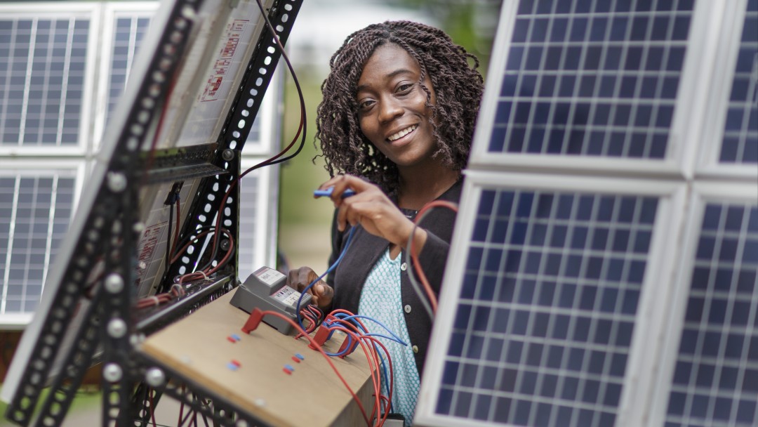 junge Arbeiterin an einer Photovoltaikanlage in Afrika