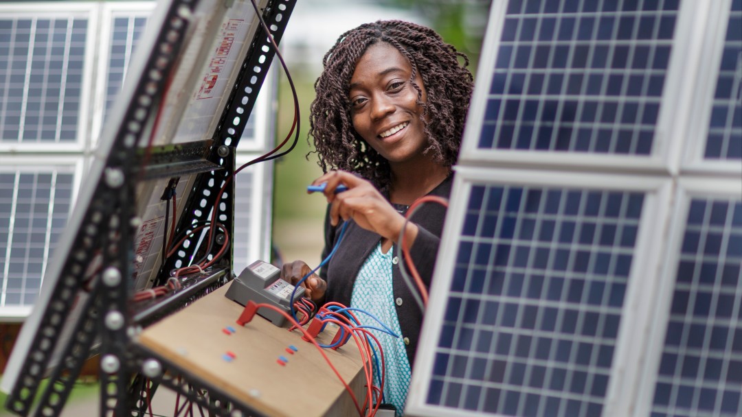 junge Arbeiterin an einer Photovoltaikanlage in Afrika