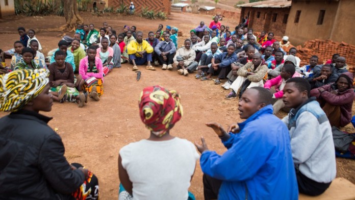viele junge Menschen in Malawi sitzen in einem Kreis, im Vordergrund wird diskutiert
