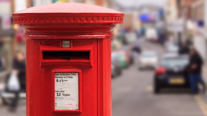 roter englischer Briefkasten mit Stadt im Hintergrund 