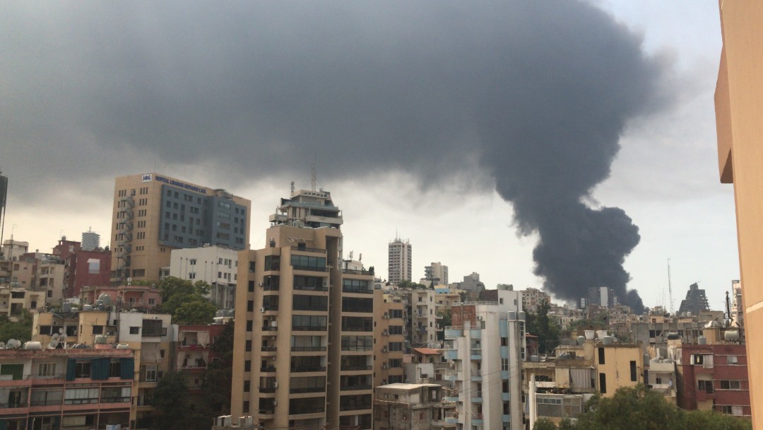 View over the skyscrapers of the city of Beirut shows the big dark explosion cloud. 