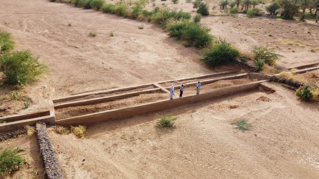 Ausgetrocknetes Flussbett mit Damm auf dem drei Männer stehen 