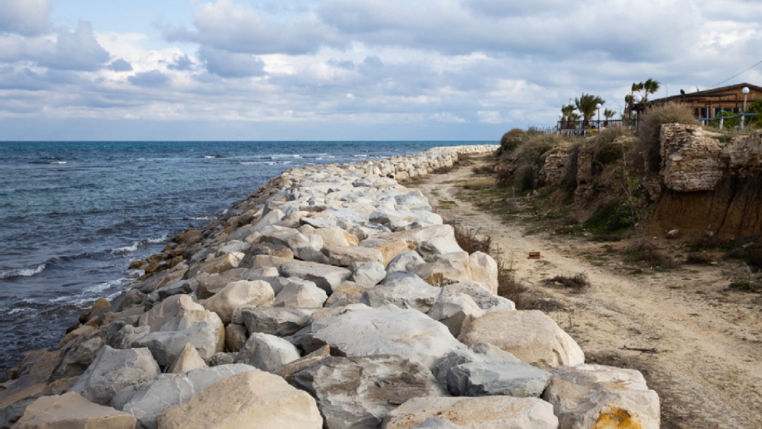 Küstenweg in Tunesien, der durch Wellenbrecher in Form von Felsen vom Meer getrentt ist.