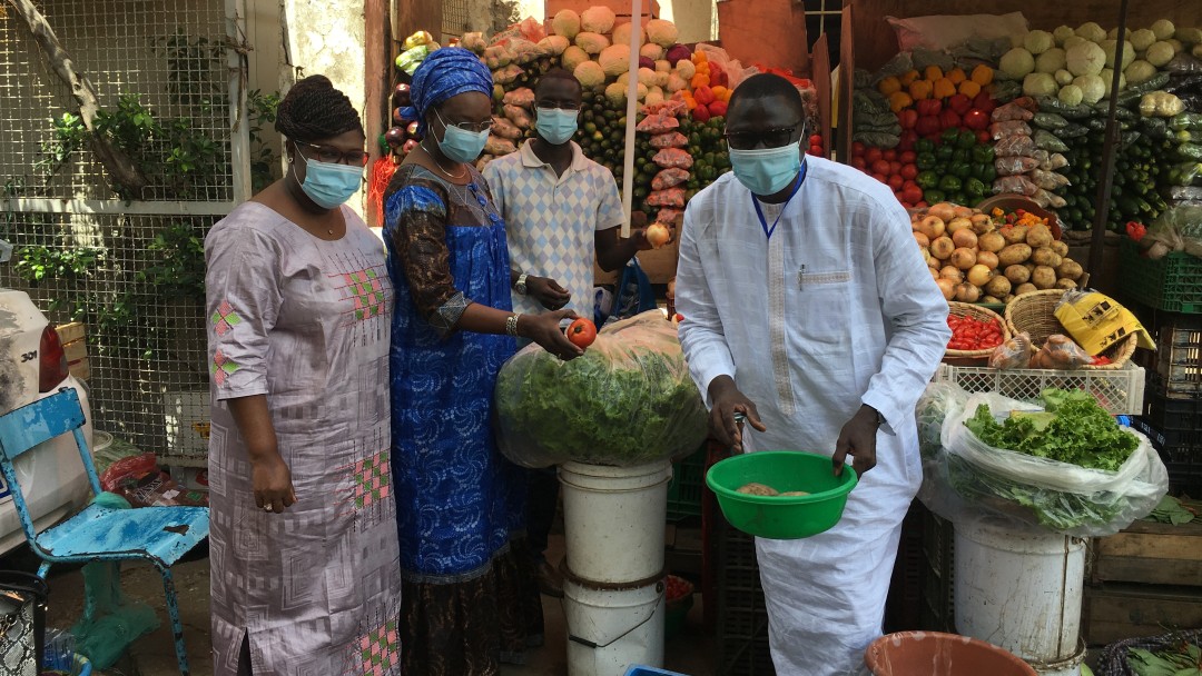 Mitarbeiterinnen des KfW Büros Dakar beim Obsteinkauf auf dem Markt. Alle tragen eine Maske. 