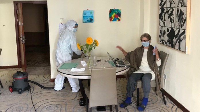 Reinigungskraft mit Schutzkleidung im Hotelzimmer 