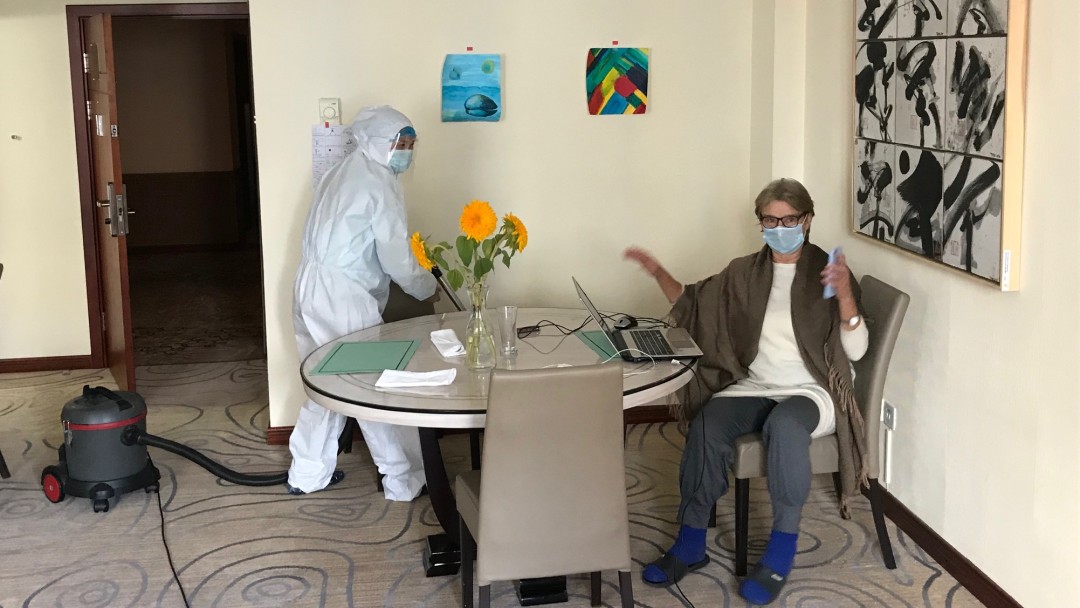 Cleaner in protective clothing in hotel room.