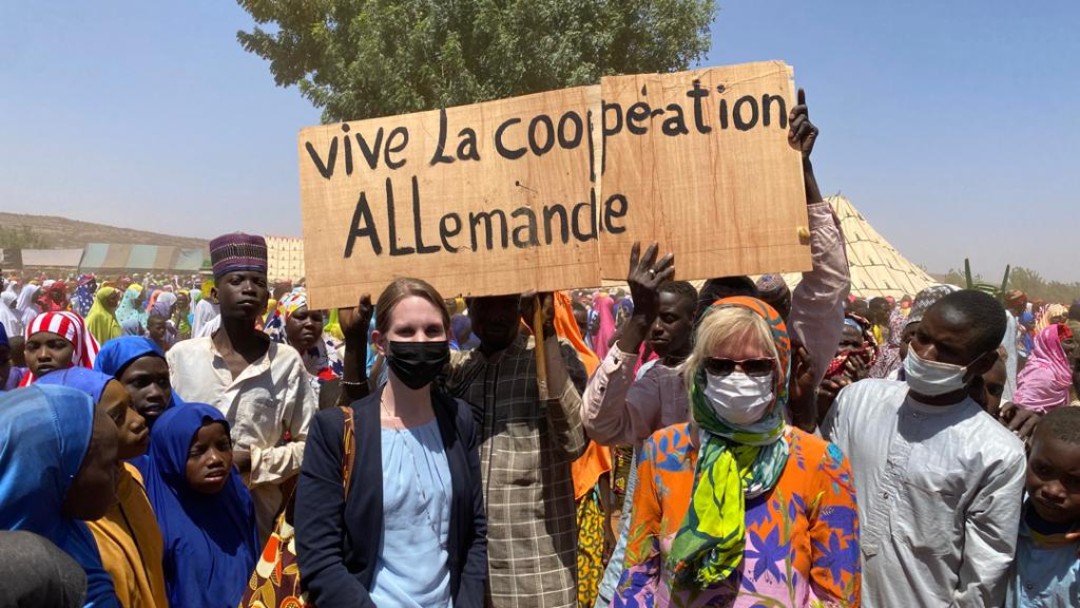 Christine Plastrotmann and KfW Office Director Kerstin Laabs with children in front of the sign "Vive la coopération allemande". 