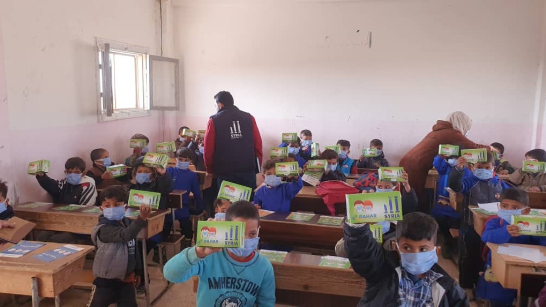 Schutzmasken werden im Klassenzimmer an die Kinder verteilt 