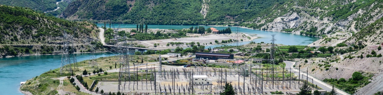 A power supply site on a river, mountains in the background