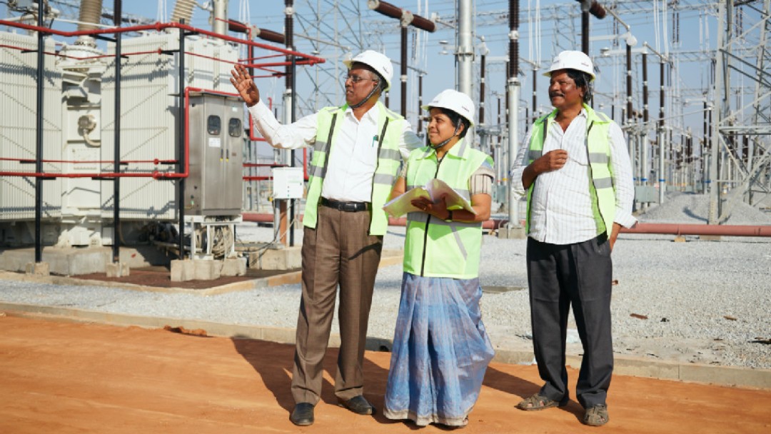 Drei Personen schauen sich die Umspannstation in Hindupur an