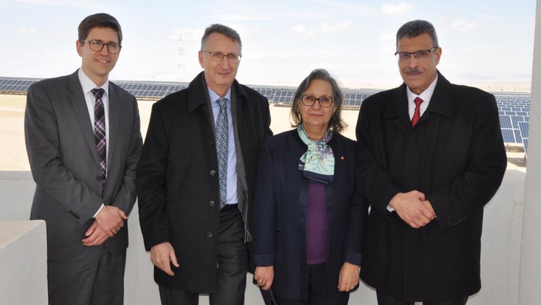 four people in front of solar power plant