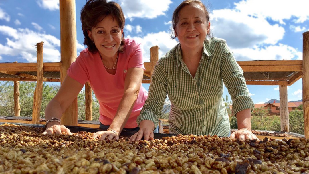 Two coffee farmers smiling in the camera with coffee in their hands.