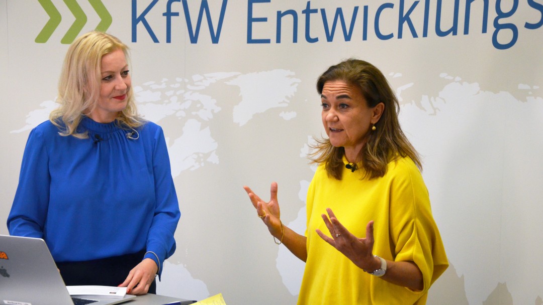 Zwei Frauen mit KfW Entwicklungsbank Logo hinter ihnen