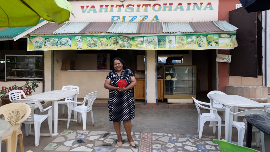 A smiling woman in front of her pizzeria. 