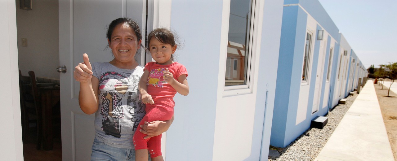 Frau mit Kind vor einer Sozialbau-Wohnung