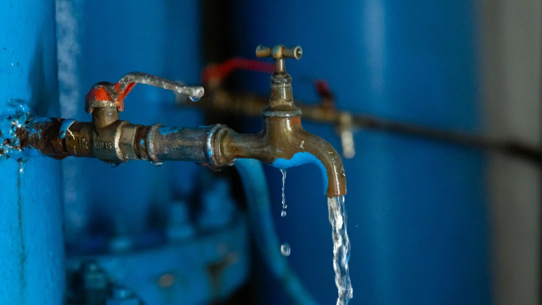 Water flows from a tap into a plastic cup.