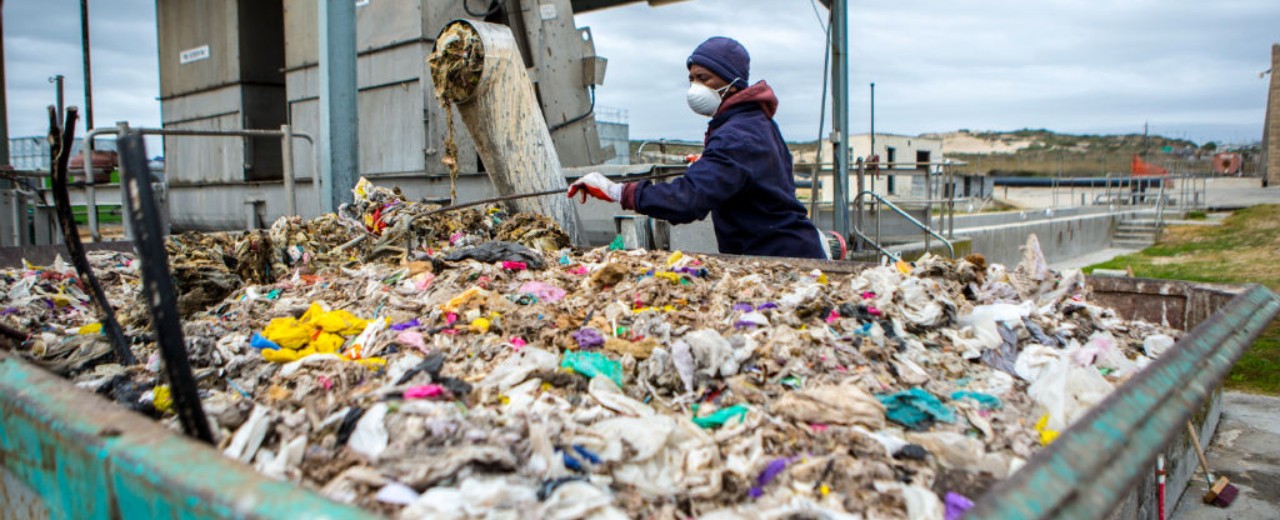 Sewage treatment plant worker in front of a container with waste