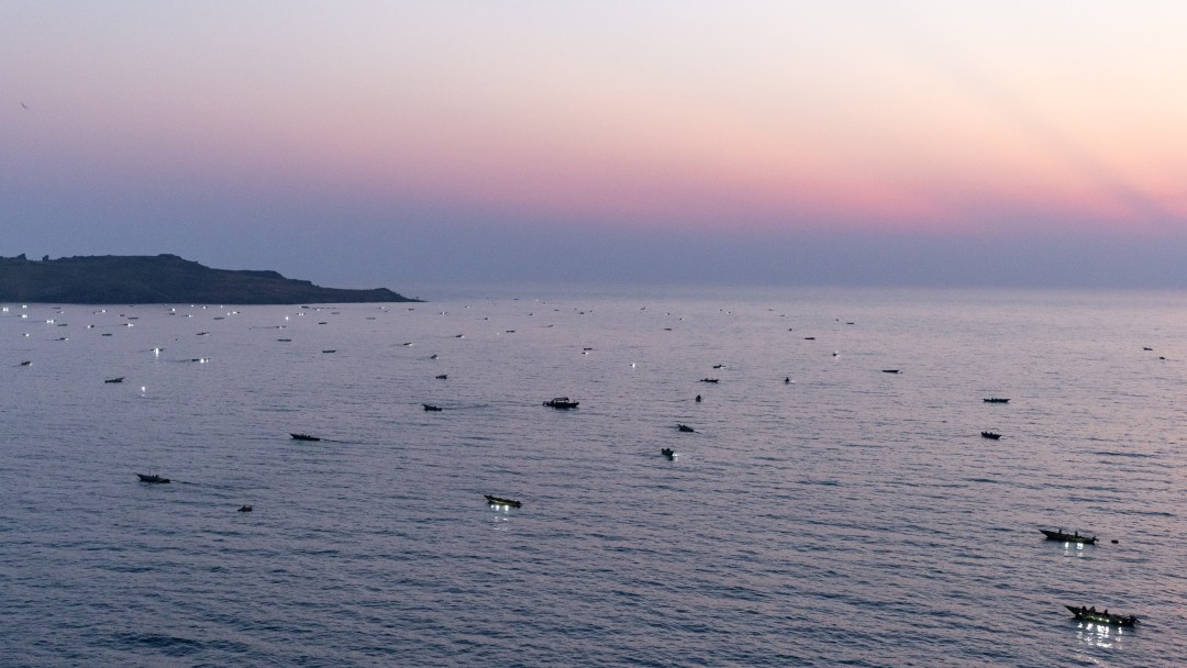Blick auf den See im Sonnenuntergang mit vielen Fischerbooten auf dem Wasser.