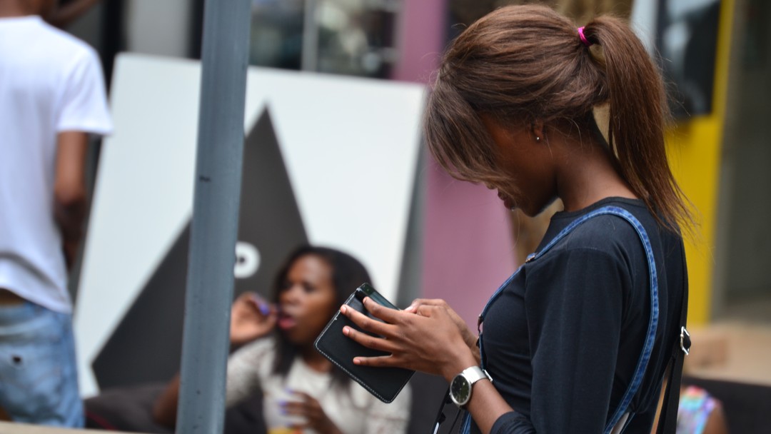 A young woman looks down on her smartphone