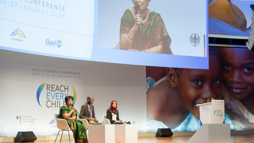 A woman and two men on a stage talking to each other