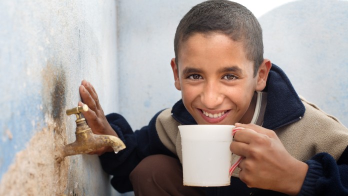 Junge trinkt aus Tasse mit sauberem Trinkwasser