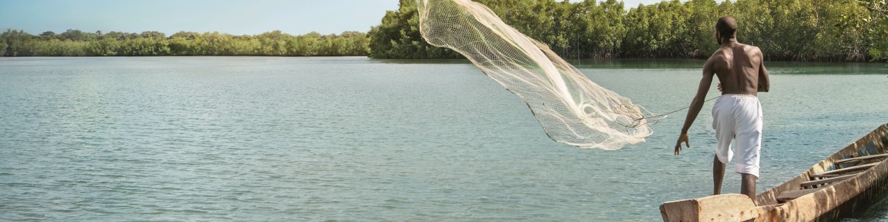 Ein Fischer wirft auf See sein Netz aus