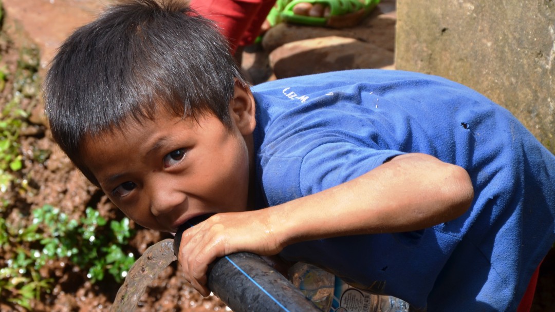 Child drinks water from hosepipe