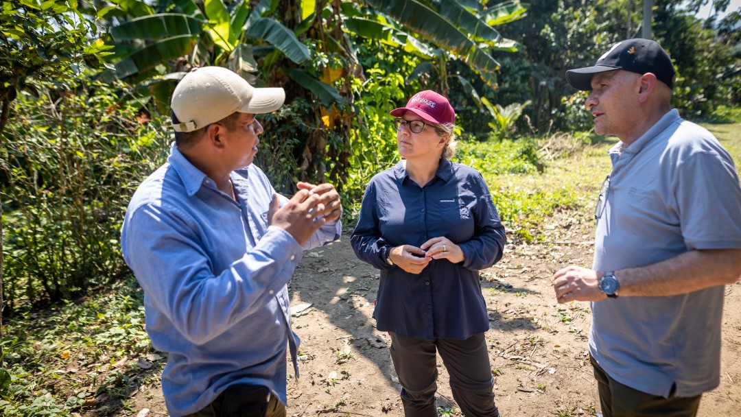 A woman with two men standing outside on a workfield