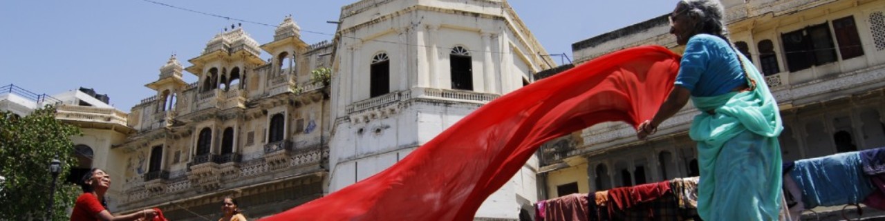 Indische Frauen stehen mit einem roten Tuch auf einer Treppe