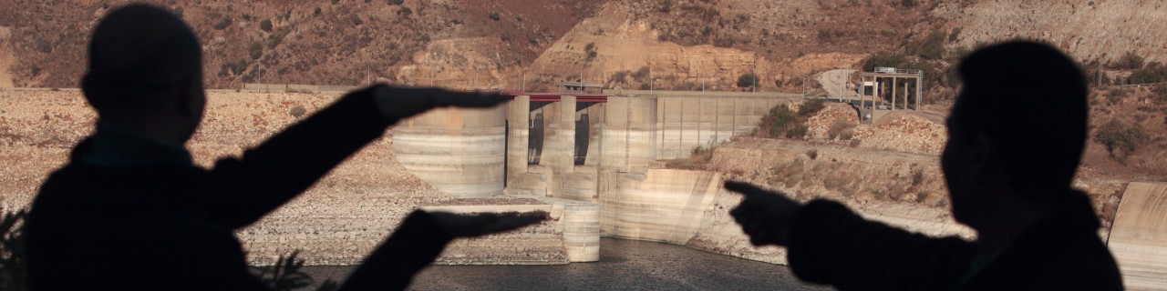 Two people pointing at a dam