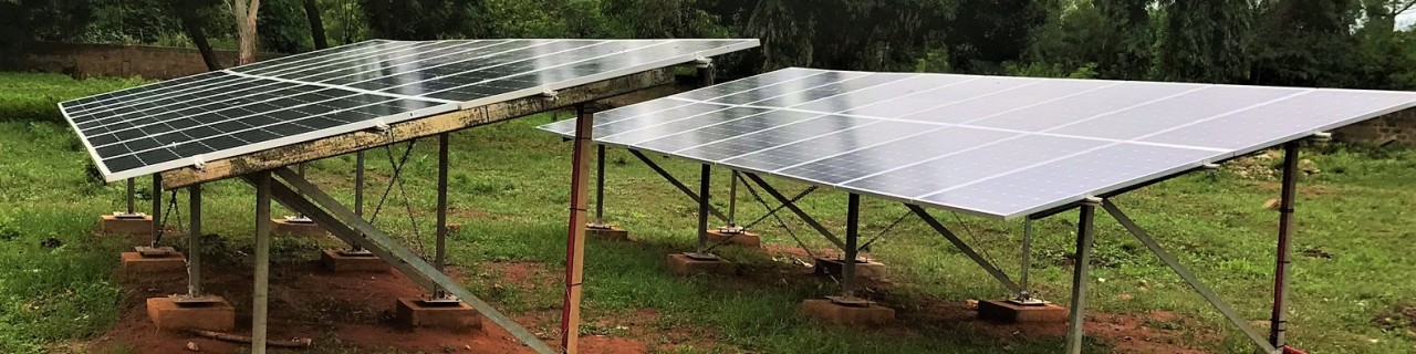 two solar panels on a meadow, trees in the background