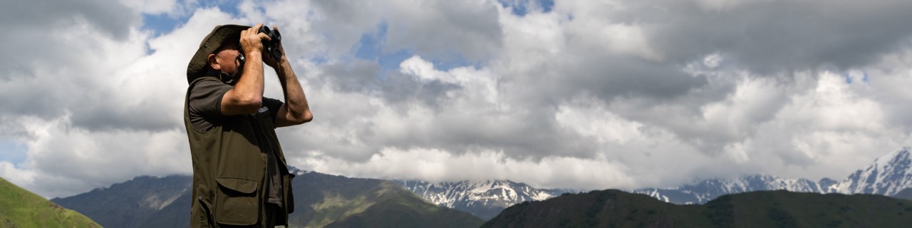 A ranger looks into the sky with binoculars.