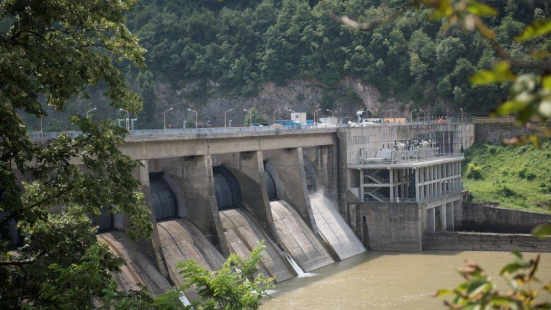 A dam, next to a forest and rocks