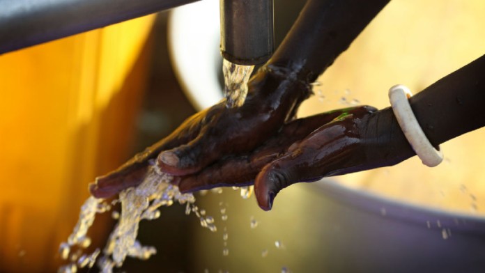 Washing hands under running water from a well