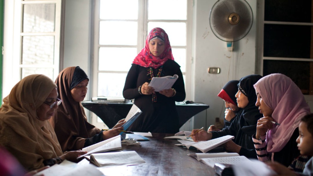 Frauen mit Kopftuch in einer Fraueninitiative, die einen Mikrokredit erhalten hat, beim gemeinsamen Lernen in Arbeitsbüchern