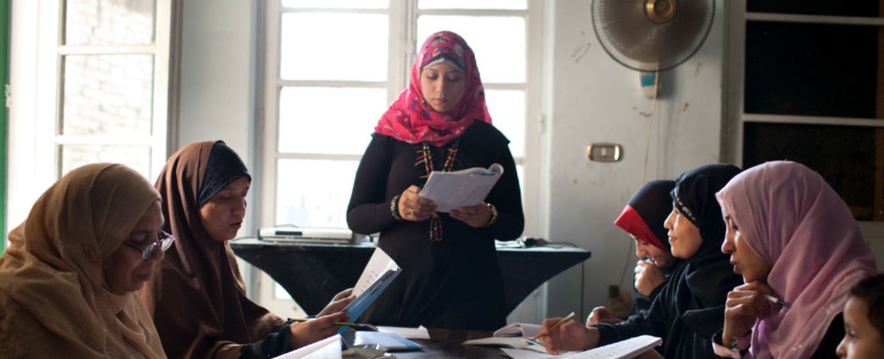Frauen mit Kopftuch in einer Fraueninitiative, die einen Mikrokredit erhalten hat, beim gemeinsamen Lernen in Arbeitsbüchern