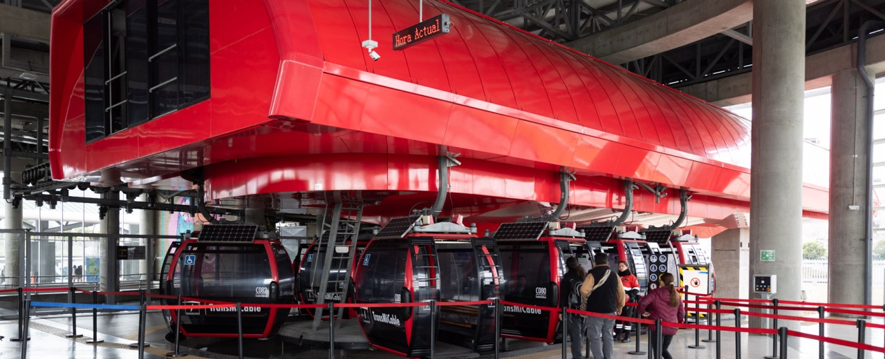 Several gondolas are visible at the gondola station, where people are waiting.