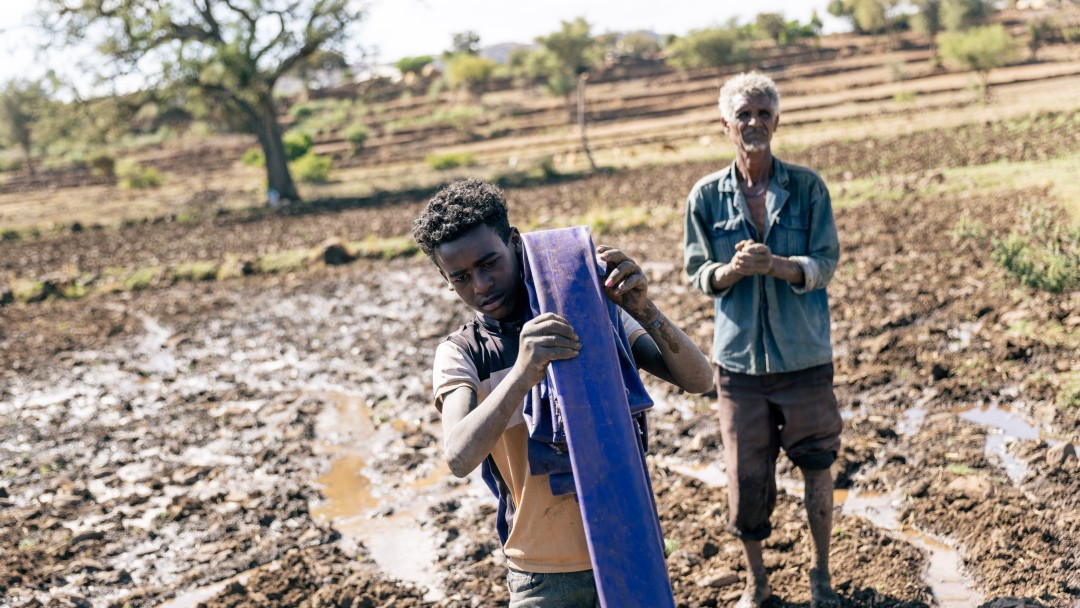 Vater und Sohn auf dem Land mit einem Wasserschlauch in der Tigray-Region in Äthiopien 