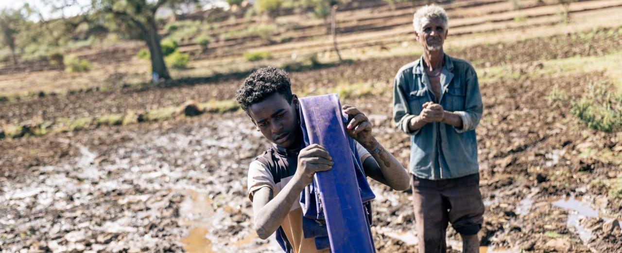 Vater und Sohn auf dem Land mit einem Wasserschlauch in der Tigray-Region in Äthiopien 