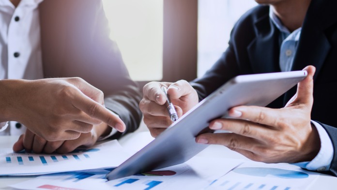 Two businessmen planing an investment and working with a tablet