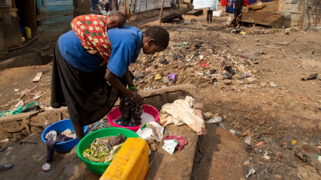 Woman with child on back doing laundry