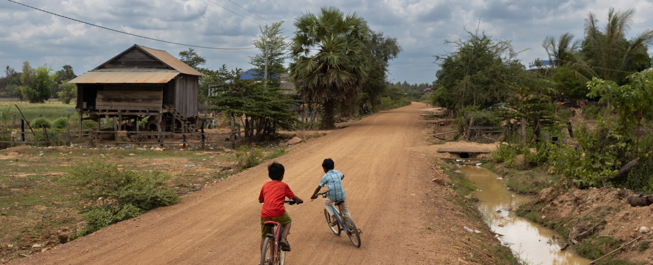 Two children ride their bikes on a road.