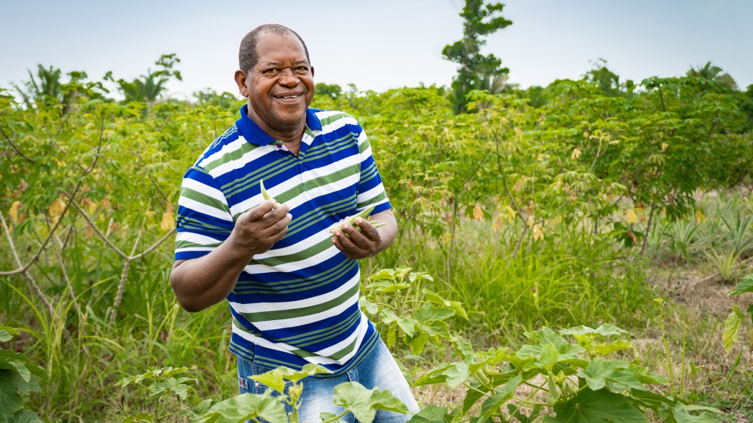 Man between bushes and holding vegetables in hand