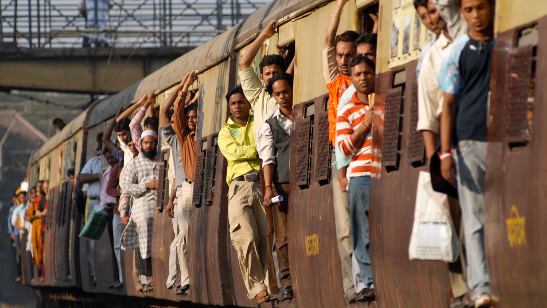 Close-up of a moving train with some people standing in its doors. 