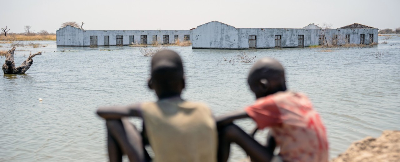 Children look at flooded buildings