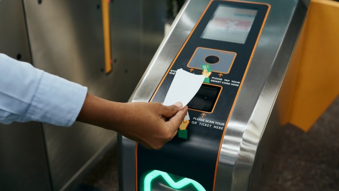 eine Hand führt ein Ticket in den Automaten der Metro in Nagpur
