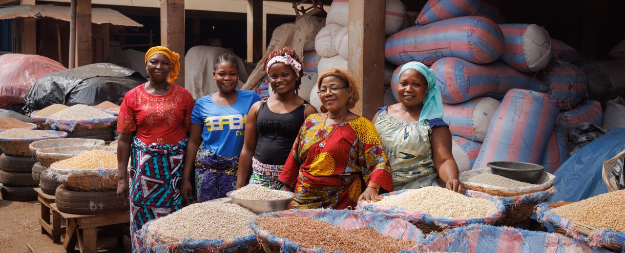 Frauen mit Getreidebehältern vor einer Markthalle