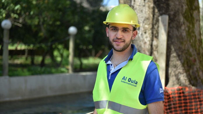 Der 21-jährige libanesische Student Sarkis Farchakh des WASH-Programms mit Arbeitskleidung und -helm auf einer Baustelle