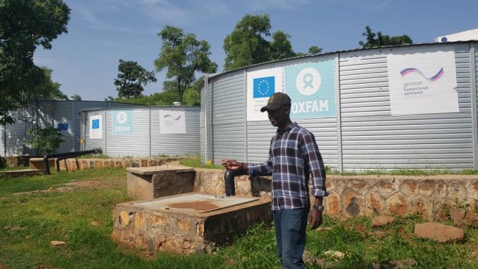 A man standing in Front of Water tanks